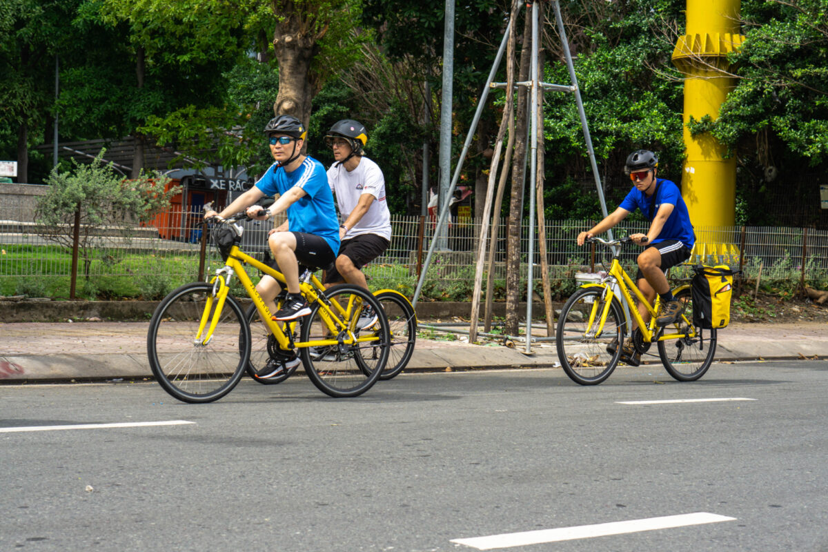 Cyclists ride along a sunny city street during one day in Ho Chi Minh City - Jackfruit