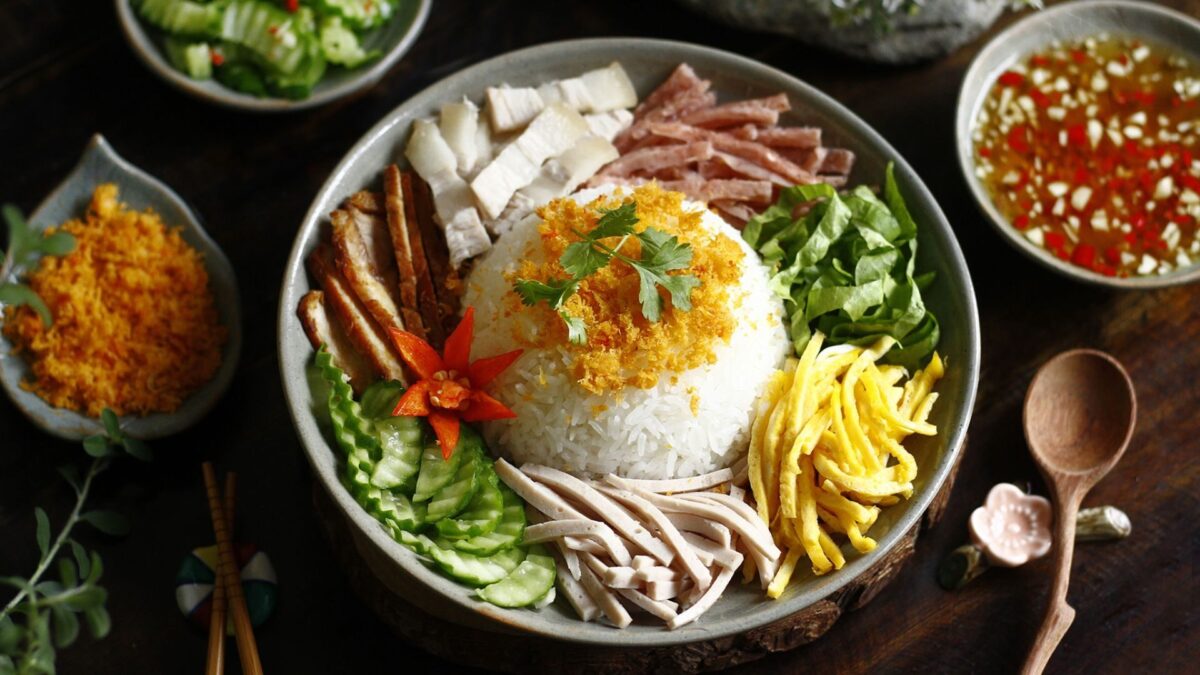 cơm âm phủ with rice, grilled pork, egg, herbs, pickles, and vegetables - hue food - Jackfruit