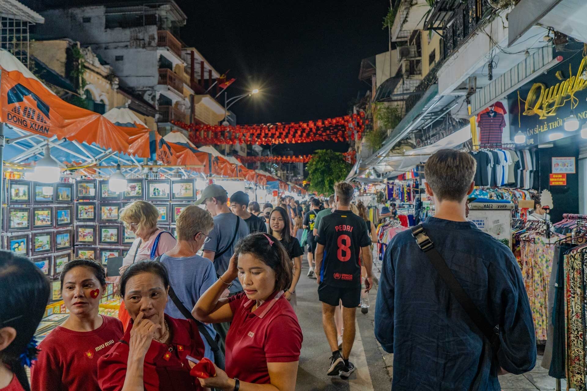 Tourists browsing a busy stall at the night market Hanoi, Old Quarter - Jackfruit Adventure
